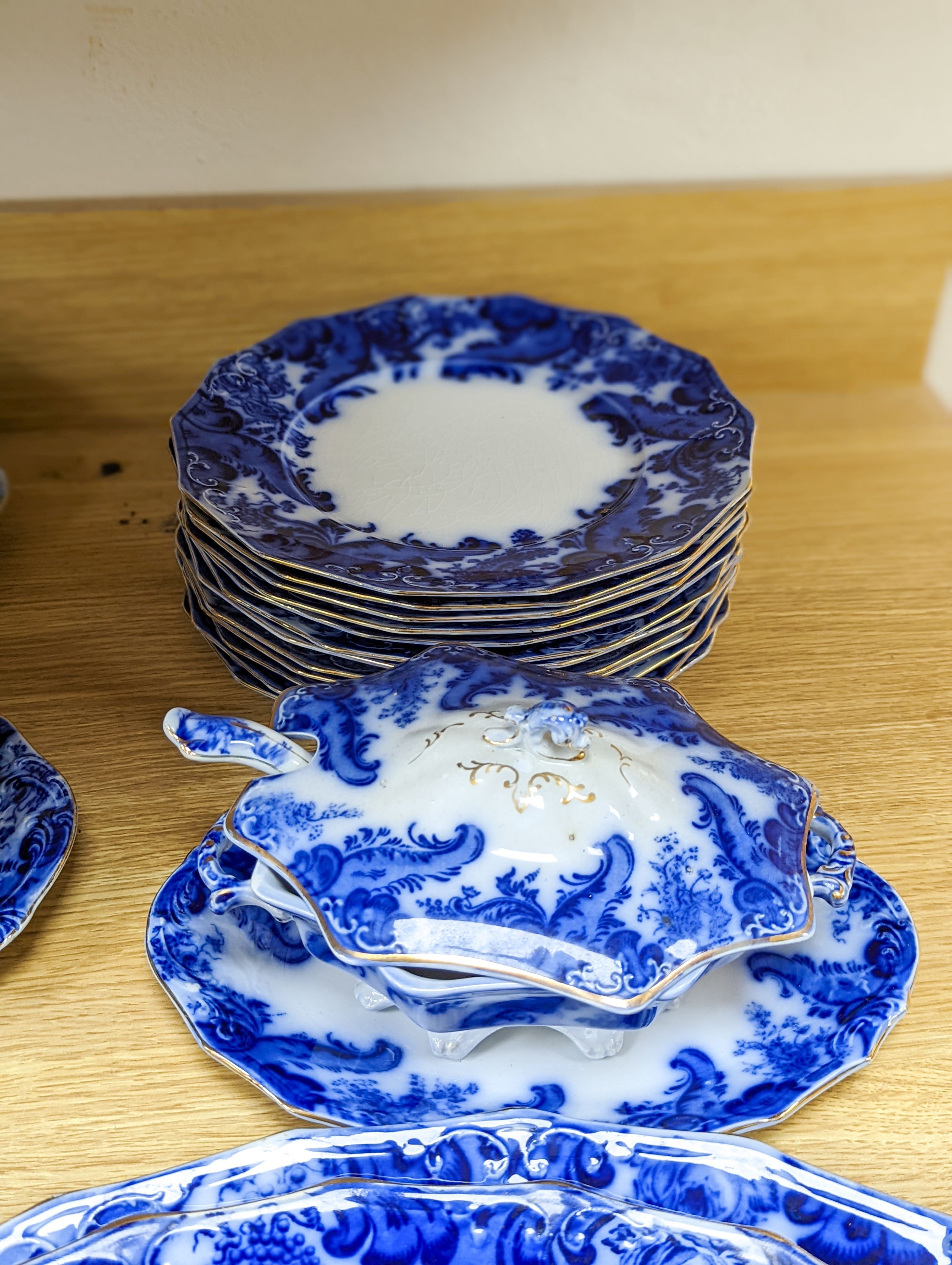 A W. H. Grindley Argyle pattern flow blue dinner service, c.1900 mostly for 12 place settings, two sauce tureens, covers and stands, two vegetable tureens and covers, two gravy boats, and six graduated meat dishes
